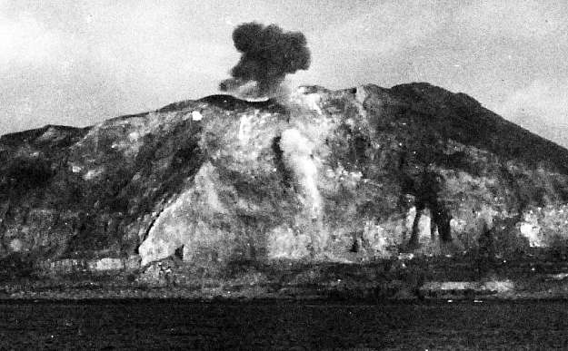 Planes strafing Iwo Jima, with Mt. Suribachi smoking from the bombs. U.S. Official Navy photograph, now in the collections of the National Archives.